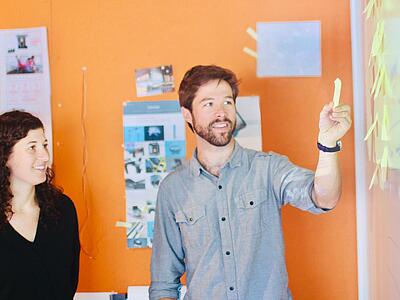 2 Menschen die an einem Whiteboard Klebezettel betrachten